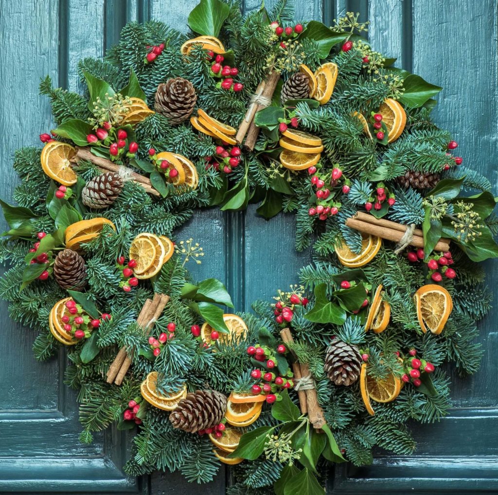 Christmas door wreath decorated with pinecones, dried oranges and cinnamon sticks