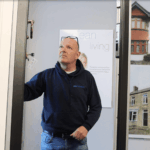 Team member opening a display door beside a poster showing window and door styles