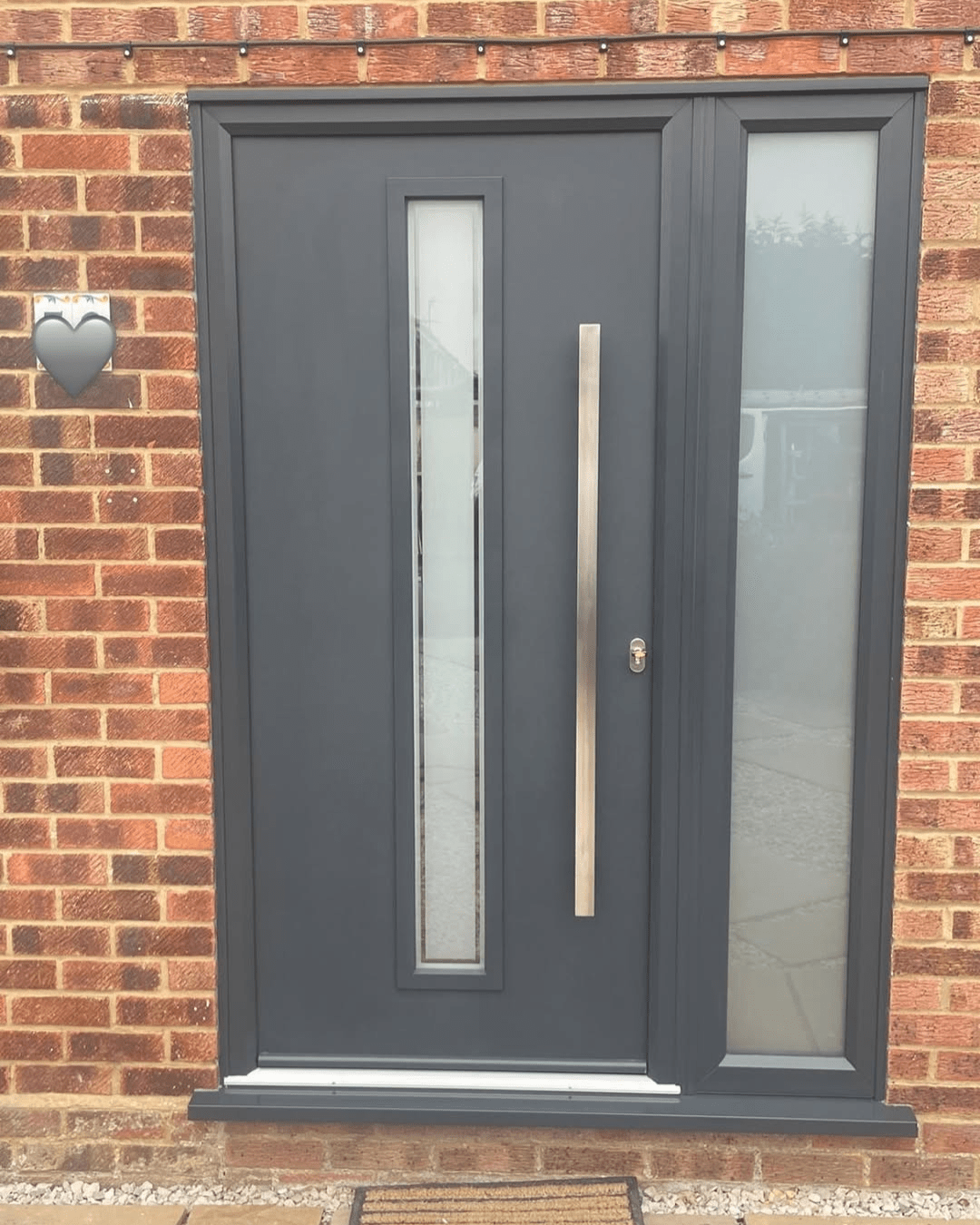 Anthracite grey front door with narrow vertical window and frosted right side window