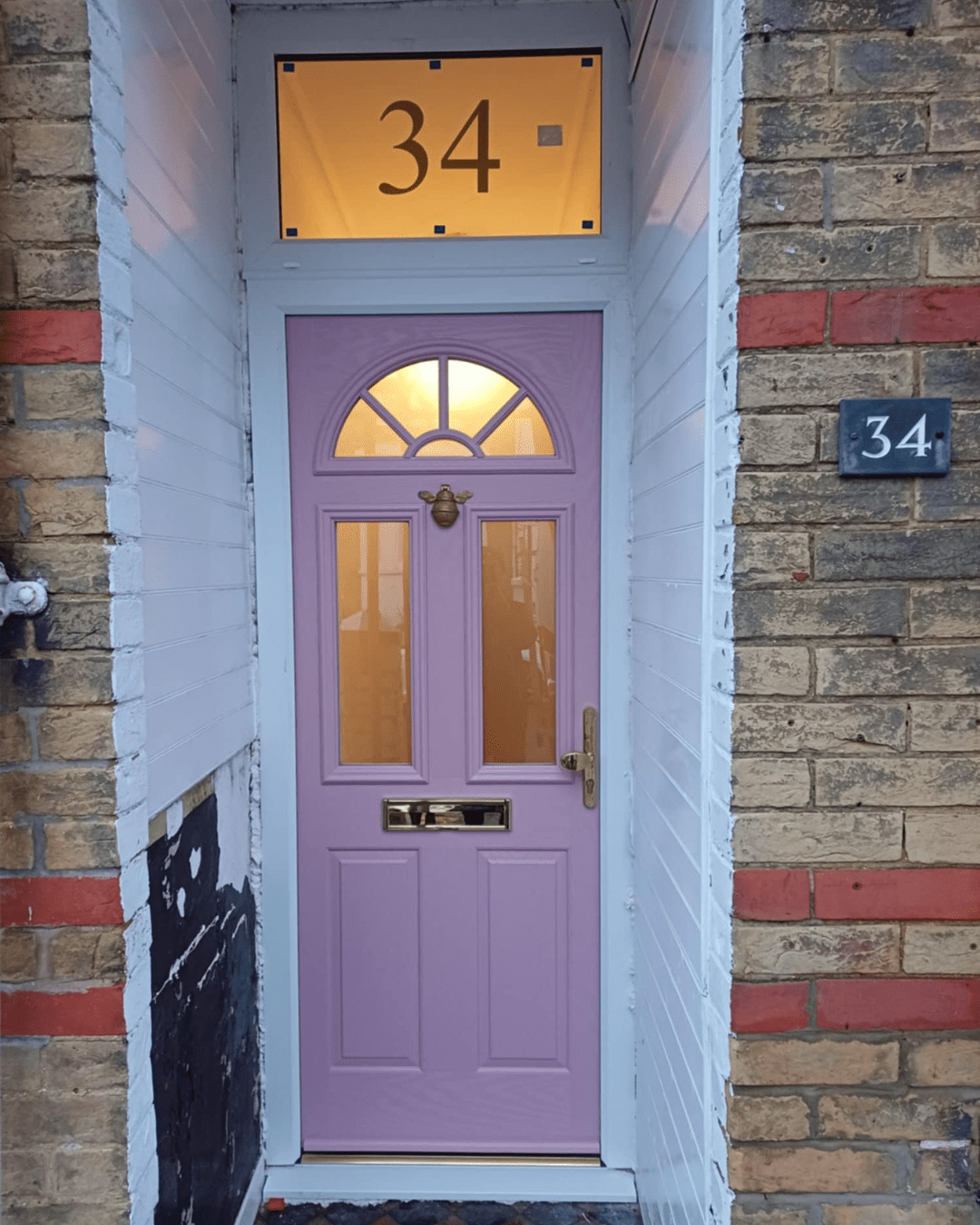Dusty pink front door with arched top window and house number 34 on upper window